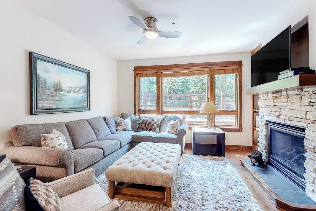 A living room with a sectional sofa, a fireplace, a television, and a painting on the wall.