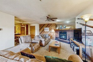 A living room with leather sofas, a coffee table, a fireplace, and a ceiling fan. - Spacious, in-town condo with balcony, pools, hot tub, tennis - walk to lifts (Breckenridge)