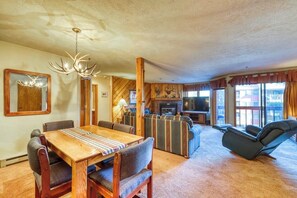 A cozy living room with a wooden dining table, sofas, a TV, and a fireplace. - Ideally located condo with pool, hot tubs & sauna - walk to lifts & Main Street (Breckenridge)