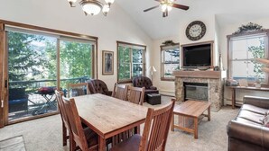 A spacious living area with a fireplace, dining table, and comfortable seating. - Main Street condo with mountain view, fireplace, pool & hot tubs - walk to lifts (Breckenridge)