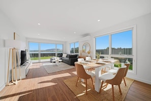 A spacious living area with a dining table, chairs, a sofa, and a TV. - The Spoonbill Retreat | Water Views Family Escape (Sorell)
