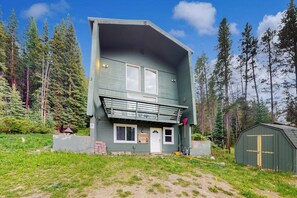 A two-story building with a balcony, surrounded by a forest. - 3-Story Hideaway with Game Room & Direct Forest Access — Dogs Welcome! (Breckenridge)