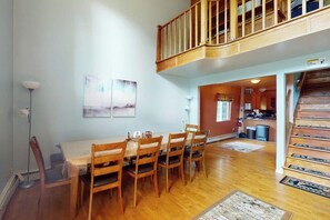 A dining area with a wooden table and chairs, a staircase, and a view into the kitchen. - 3-Story Hideaway with Game Room & Direct Forest Access — Dogs Welcome! (Breckenridge)