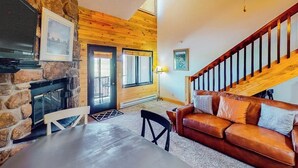 A cozy living room with a stone fireplace, wooden ceiling, and a leather sofa. - 3rd-floor retreat with balconies, in/outdoor pools, game room, gym, views (Granby)