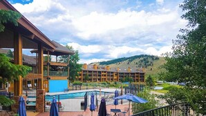 A hotel with a pool, outdoor seating, and a view of a mountainous landscape. - 3rd-floor retreat with balconies, in/outdoor pools, game room, gym, views (Granby)