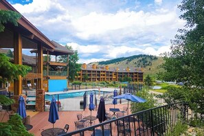 A hotel with a pool, outdoor seating, and a view of a mountainous landscape. - 3rd-floor retreat with balconies, in/outdoor pools, game room, gym, views (Granby)