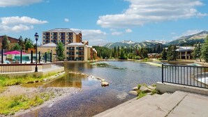 A riverside view with a building, a bridge, and mountains in the background. - Breckenridge studio, shared hot tub, gym, & pool + elevator, WiFi, walk to lifts (Breckenridge)