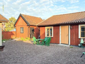 A wooden building with a gravel courtyard, a wooden door, and a window with a white frame.