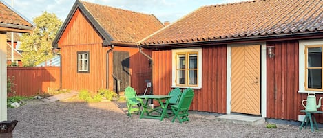 A wooden building with a gravel driveway and a table with chairs.