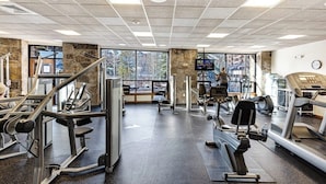 A gym with exercise equipment, large windows, and a stone pillar. - Mountain condo with pool, hot tubs, gym & steam room - near skiing & hiking (Breckenridge)