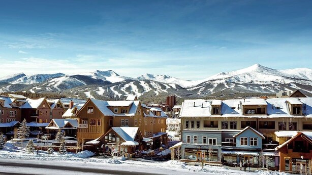 A snow-covered mountain town with wooden buildings and a ski resort in the background. - Mountain condo with pool, hot tubs, gym & steam room - near skiing & hiking (Breckenridge)