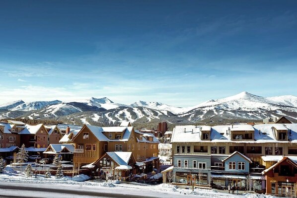 A snow-covered mountain town with wooden buildings and a ski resort in the background. - Mountain condo with pool, hot tubs, gym & steam room - near skiing & hiking (Breckenridge)