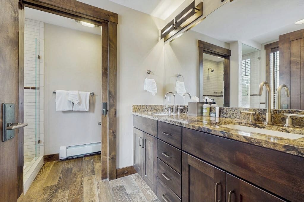 Une salle de bain dotée d’un grand miroir, de meubles en bois foncé et d’un comptoir en granit.