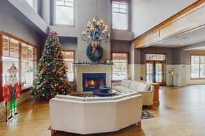 Ein geräumiges Wohnzimmer mit Kamin, Weihnachtsbaum und einer großen Chandelier.