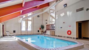 Ein überdachter Swimmingpool mit freiem Blick auf das Becken, einem Rettungsschwimmerstuhl und einem roten Sicherheitsring an der Wand.