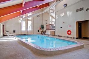 Ein überdachter Swimmingpool mit freiem Blick auf das Becken, einem Rettungsschwimmerstuhl und einem roten Sicherheitsring an der Wand.