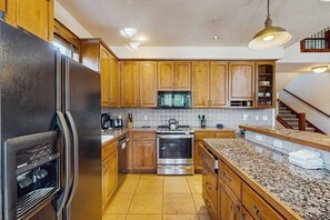A kitchen with wooden cabinets, a stainless steel refrigerator, a microwave, and an oven. - Ski-in/out, ground-floor condo with private hot tub & fireplace, close to town (Breckenridge)