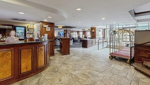 Eine Hotelhalle mit Empfangsschalter, Sitzgelegenheiten und einem Rollwagen.