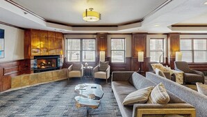 Ein geräumiges Wohnzimmer mit Kamin, bequemen Sitzmöglichkeiten und großen Fenstern.