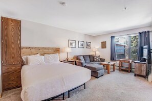 A hotel room with a large bed, a sofa, a small table, and a TV. - Skiers studio with WiFi, pool, hot tub, sauna, & balcony in downtown location (Breckenridge)
