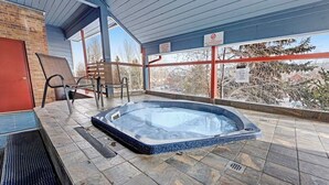 A hot tub with a tiled floor, a brick wall, and a covered patio area. - Skiers studio with WiFi, pool, hot tub, sauna, & balcony in downtown location (Breckenridge)