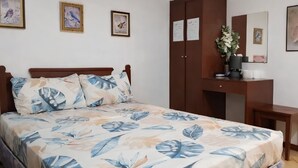 Um quarto com uma cama, guarda-roupa, escrivaninha e espelho.
