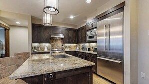 Una cocina moderna con armarios de madera oscura, electrodomésticos de acero inoxidable y encimera de granito.