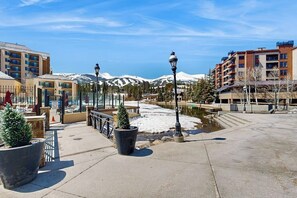 A hotel with a view of snow-capped mountains, outdoor seating, and a paved walkway. - Cozy condo on Main Street with hot tubs, pool & gym - walk to Peak 9 lifts (Breckenridge)