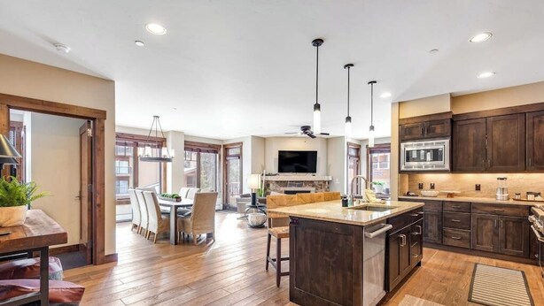 Una cocina amplia con piso de madera, armarios oscuros, una isla central y un comedor con mesa y sillas.