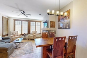A dining area with a wooden table and chairs, a ceiling fan, and a chandelier. - Walk to lifts from this centrally located condo with a pool, hot tubs & gym (Breckenridge)