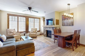 A living room with a fireplace, a dining area, and a ceiling fan. - Walk to lifts from this centrally located condo with a pool, hot tubs & gym (Breckenridge)