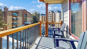 En balkon med udsigt til andre bygninger, gelænder og udendørs møbler.