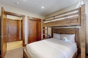 A bedroom with a bunk bed, wooden doors, and a small bedside table. - Walk to lifts from this centrally located condo with a pool, hot tubs & gym (Breckenridge)