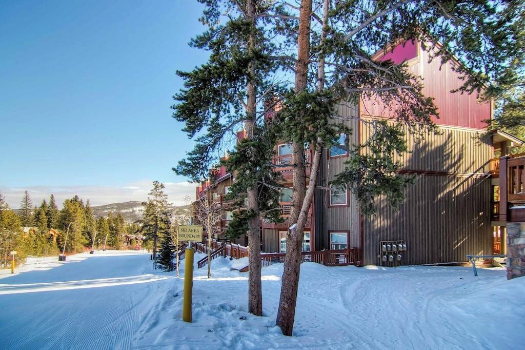 Une station de ski enneigée, avec un bâtiment doté de nombreux balcons et d’une façade en bois.