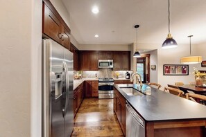 A modern kitchen with stainless steel appliances, wooden cabinets, and a central island. - Luxury condo near Peak 9 base with outdoor pool, hot tubs & gym (Breckenridge)