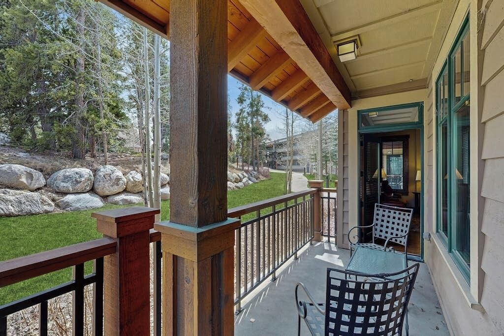 A covered outdoor area with a wooden railing, a table, and chairs.