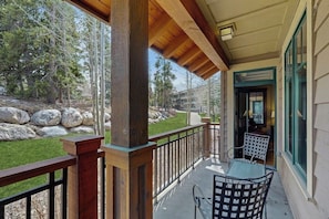 A covered outdoor area with a wooden railing, a table, and chairs. - Stellar downtown/walk-to-lifts location with outdoor pool, hot tubs & gym (Breckenridge)