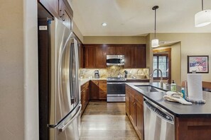 A modern kitchen with stainless steel appliances, wooden cabinets, and a granite countertop. - Stellar downtown/walk-to-lifts location with outdoor pool, hot tubs & gym (Breckenridge)