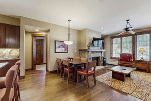 A spacious living area with a fireplace, a dining table with chairs, a sofa, and a ceiling fan. - Stellar downtown/walk-to-lifts location with outdoor pool, hot tubs & gym (Breckenridge)