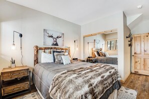 Ein Schlafzimmer mit einem großen Bett, einem Nachttisch aus Holz, einem Spiegel und einem Hirschbild an der Wand.