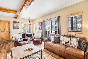 Ein gemütliches Wohnzimmer mit einer braunen Ledersofa, einem Holztisch und einem Essbereich mit Tisch und Stühlen.
