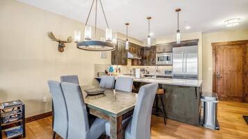 Una cocina moderna con una isla central, electrodomésticos de acero inoxidable y un comedor con sillas azules.