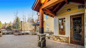A building with a stone pillar, a wooden porch, and a door with a leaf design. - Walk-to-lift condo with beautiful view, outdoor pool, hot tubs & fitness center (Breckenridge)