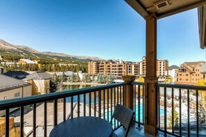A balcony with a view of a mountain, a pool, and surrounding buildings. - Luxury condo with large balcony, great views, pool & hot tubs - walk to lifts (Breckenridge)