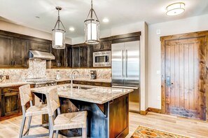 A modern kitchen with dark wood cabinets, stainless steel appliances, and a marble island. - Luxury condo with large balcony, great views, pool & hot tubs - walk to lifts (Breckenridge)