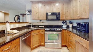 Eine moderne Küche mit Holzausstattung, Edelstahlgeräten und Granitarbeitsplatten.