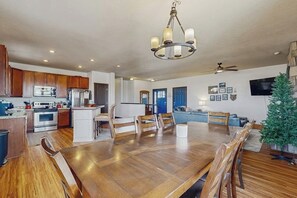 Una cocina amplia con gabinetes de madera, un comedor con una gran mesa de madera y una sala de estar con sofá y televisor.