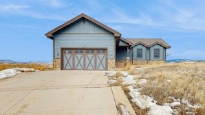 A two-story house with a garage, a front porch, and a clear sky. - Mountain getaway with hot tub, game room, fireplace, and modern interior (Granby)