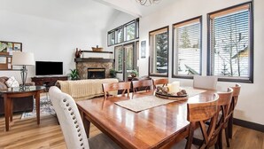 Un salon spacieux doté d’une cheminée, d’un coin repas et de grandes fenêtres.