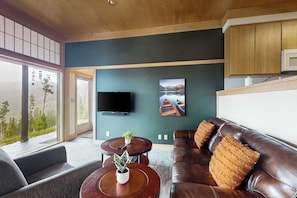 A modern living room with a sofa, a coffee table, and a TV mounted on the wall. - Cozy home with full kitchen, private patio & mountain views (Grand Lake)